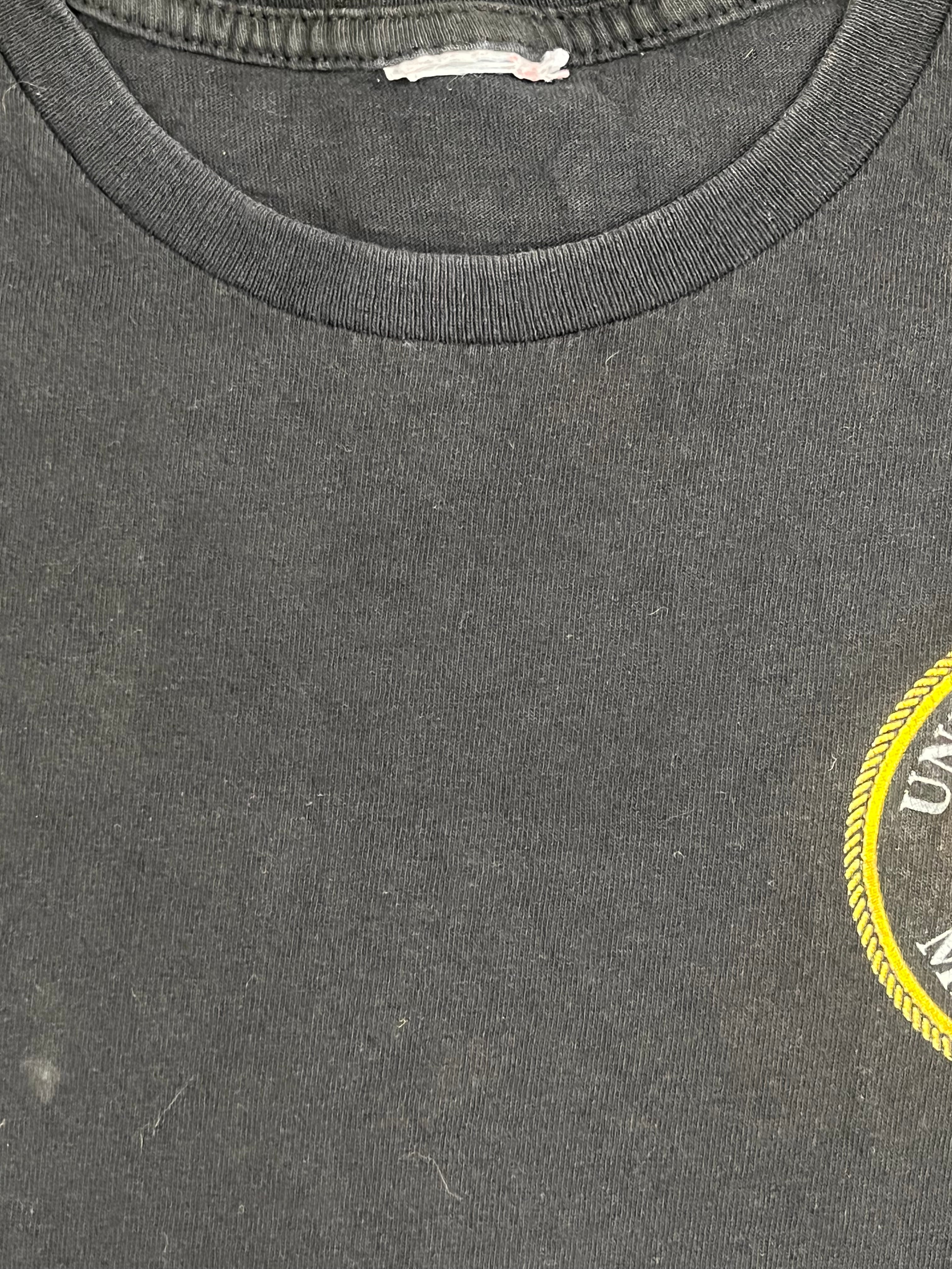 Close-up of a dark gray heathered fabric surface with a partial yellow circular graphic at the top edge and a ribbed collar trim on the left side.