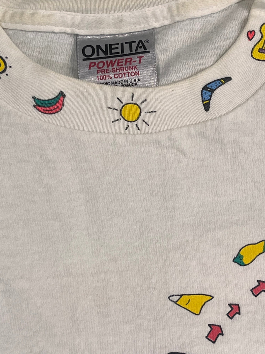 Close-up of a white Oneita Power Cotton t-shirt featuring colorful cartoon graphics of crayons, a sun, and arrows, with the brand tag visible inside the collar.