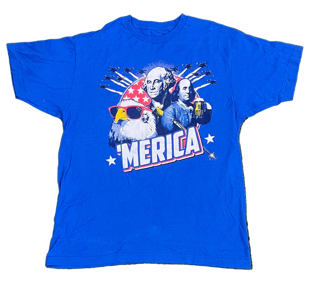 A royal blue short-sleeve graphic t-shirt laid flat on white background The front of the shirt features a patriotic graphic with George Washington, a bald eagle wearing a red and white star-spangled hat and yellow sunglasses, and the text 'AMERICA' in white with red and blue outlines.