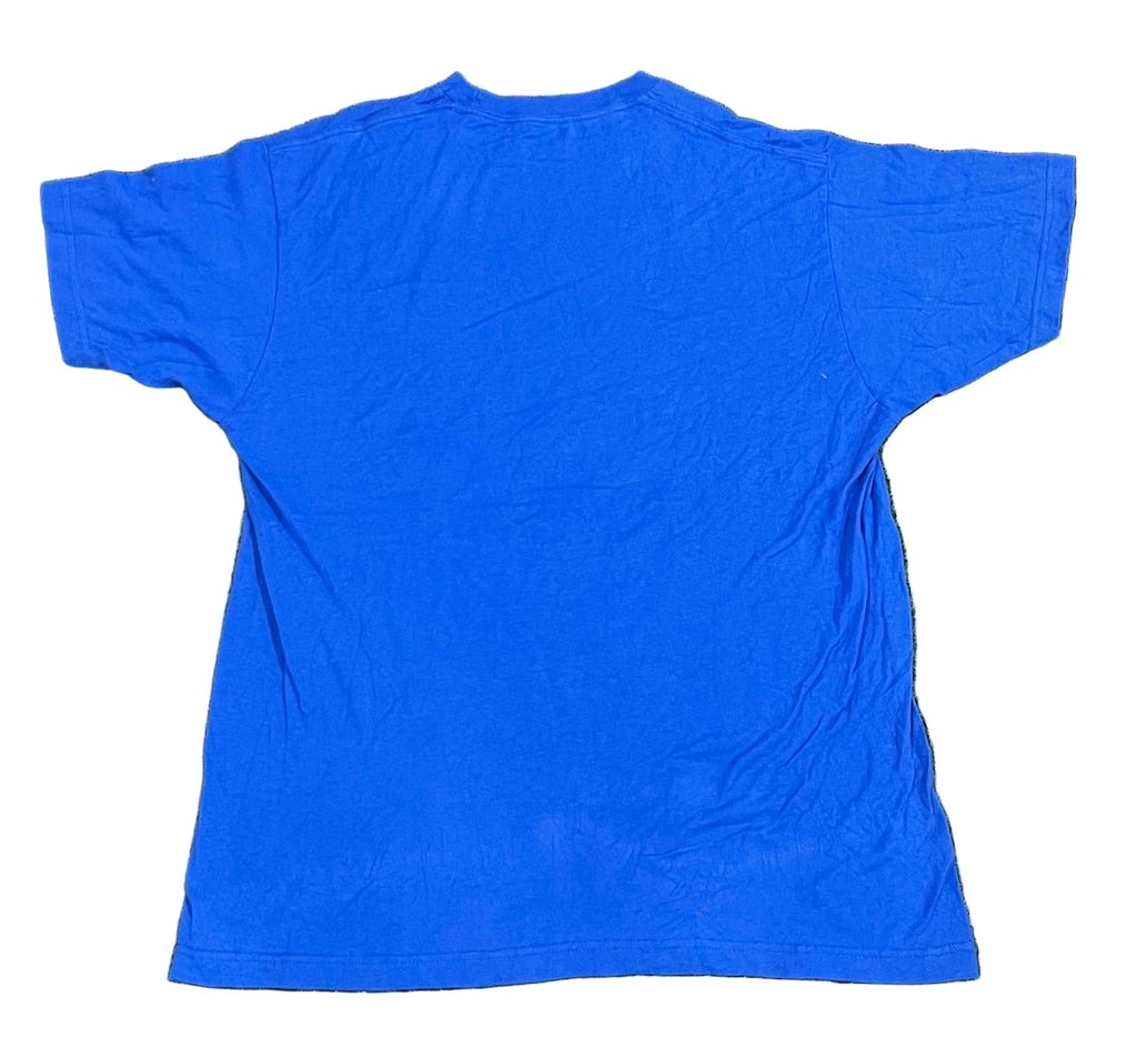 A bright blue short-sleeve t-shirt laid flat on  with background artificial turf.