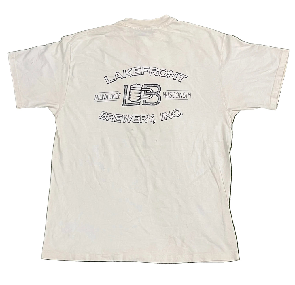 A white short-sleeve t-shirt  featuring a black outline graphic on the back that reads 'LAKEFRONT MILWAUKEE WISCONSIN BREWERY, INC' with a central 'LB' logo.