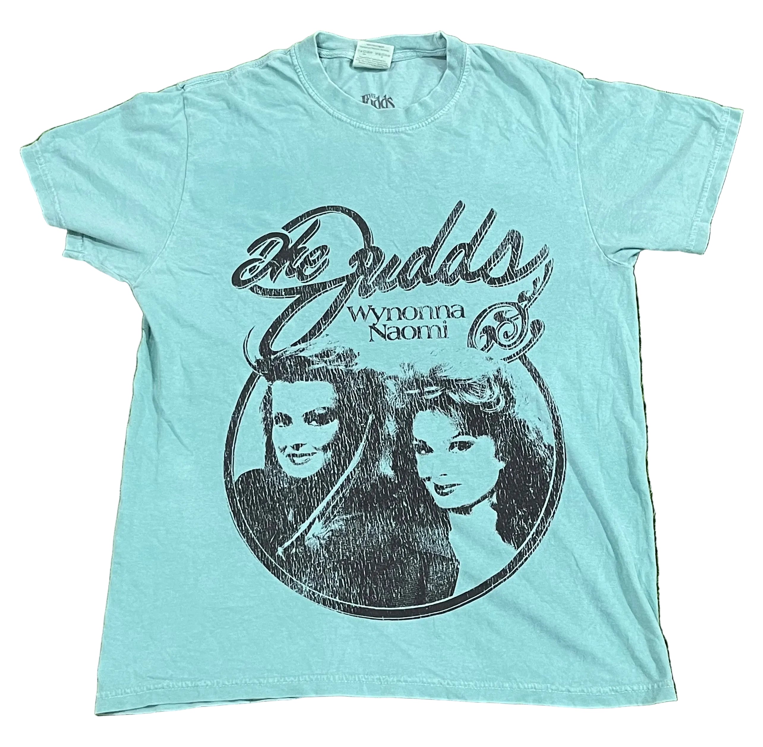 A light blue short-sleeve t-shirt The shirt features a large black distressed print reading 'The Budds' and 'Wyonna Naomi' with a circular portrait graphic of the two women.