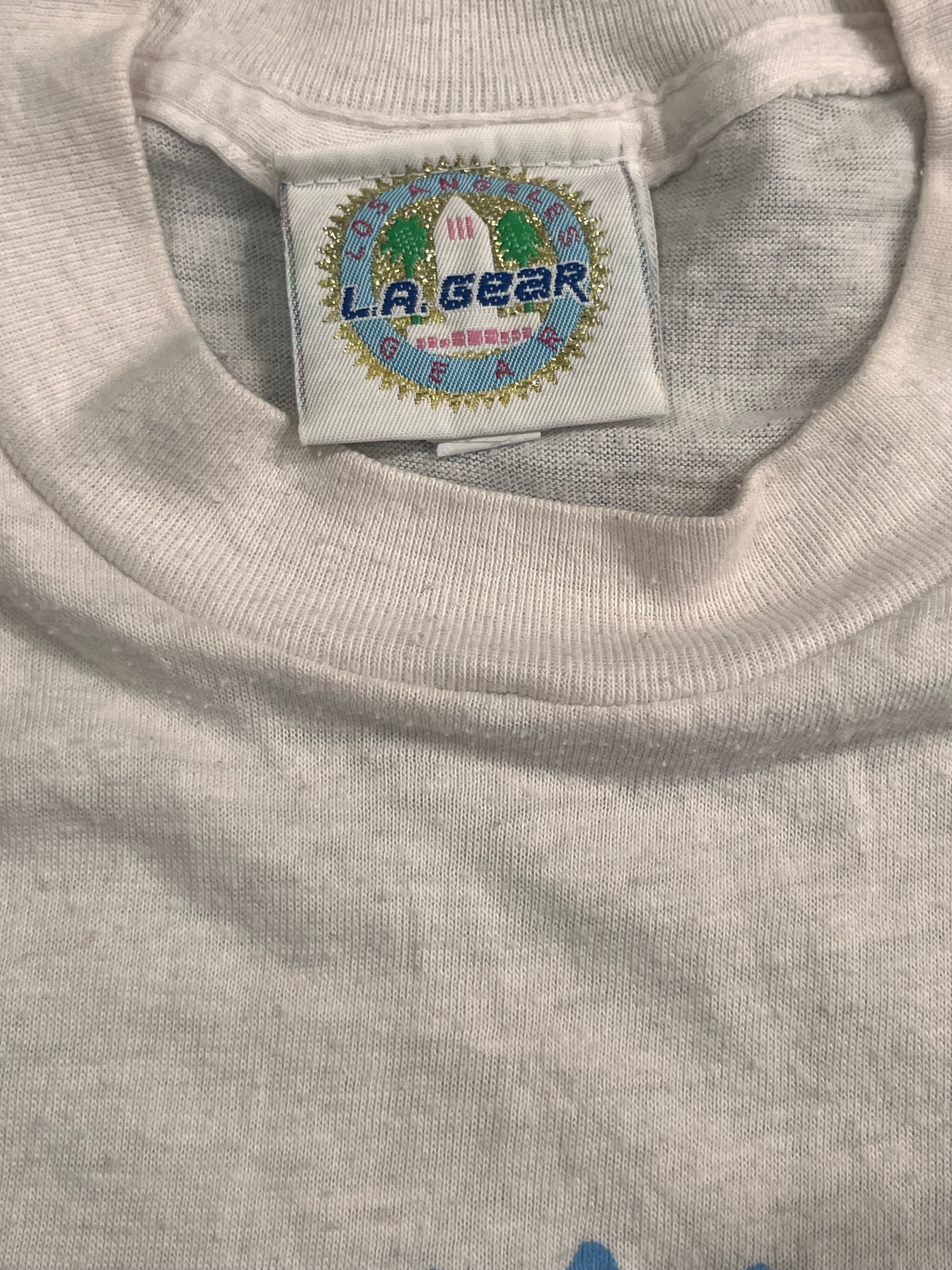 Close-up of a light gray heather crewneck t-shirt showing the inner neck label which reads 'LA GEAR'.