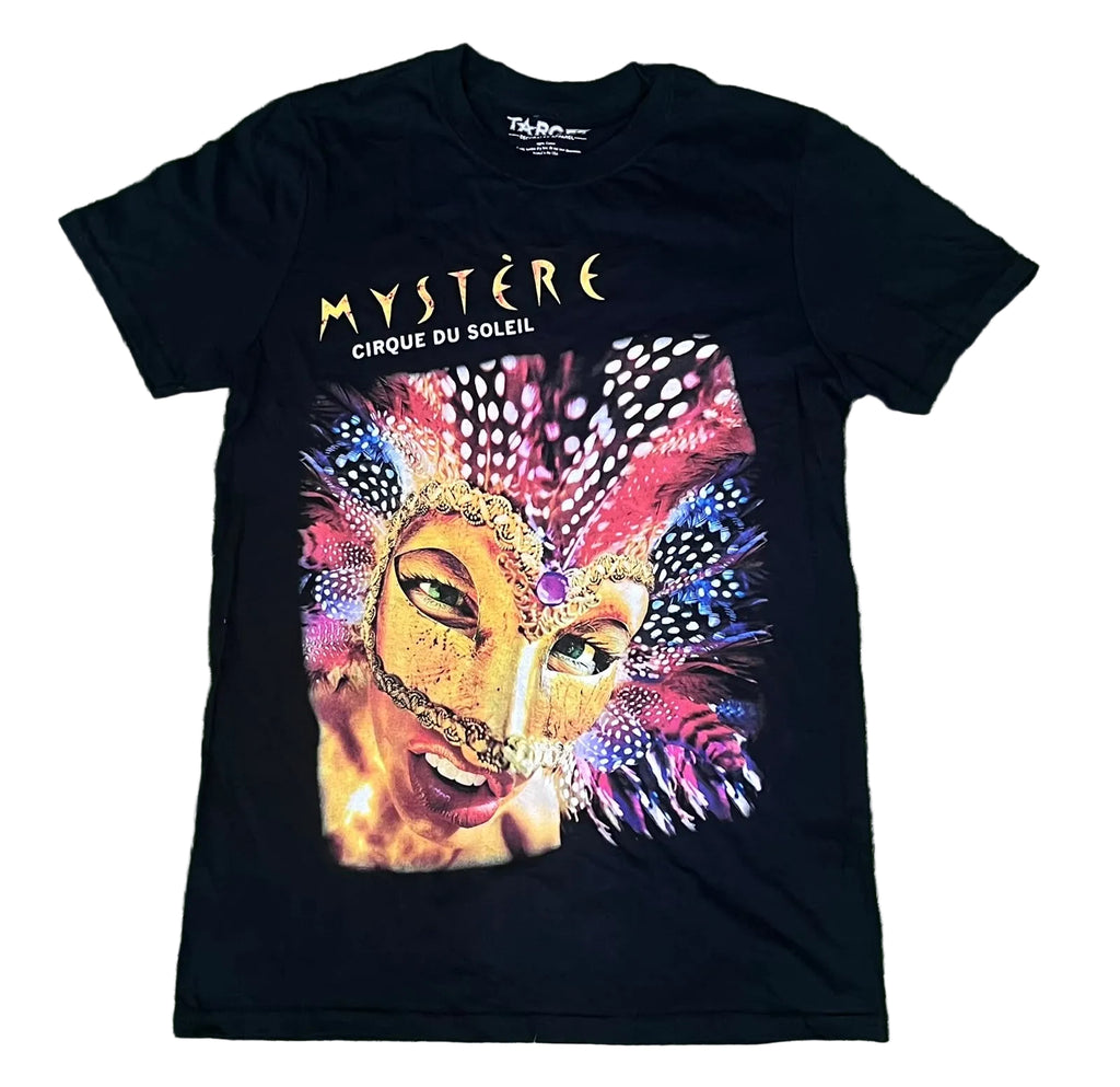 A black short-sleeve graphic T-shirt . The shirt features the words 'MYSTÈRE CIRQUE DU SOLEIL' in gold and white above a large colorful carnival mask illustration with pink, purple, blue, and gold tones.
