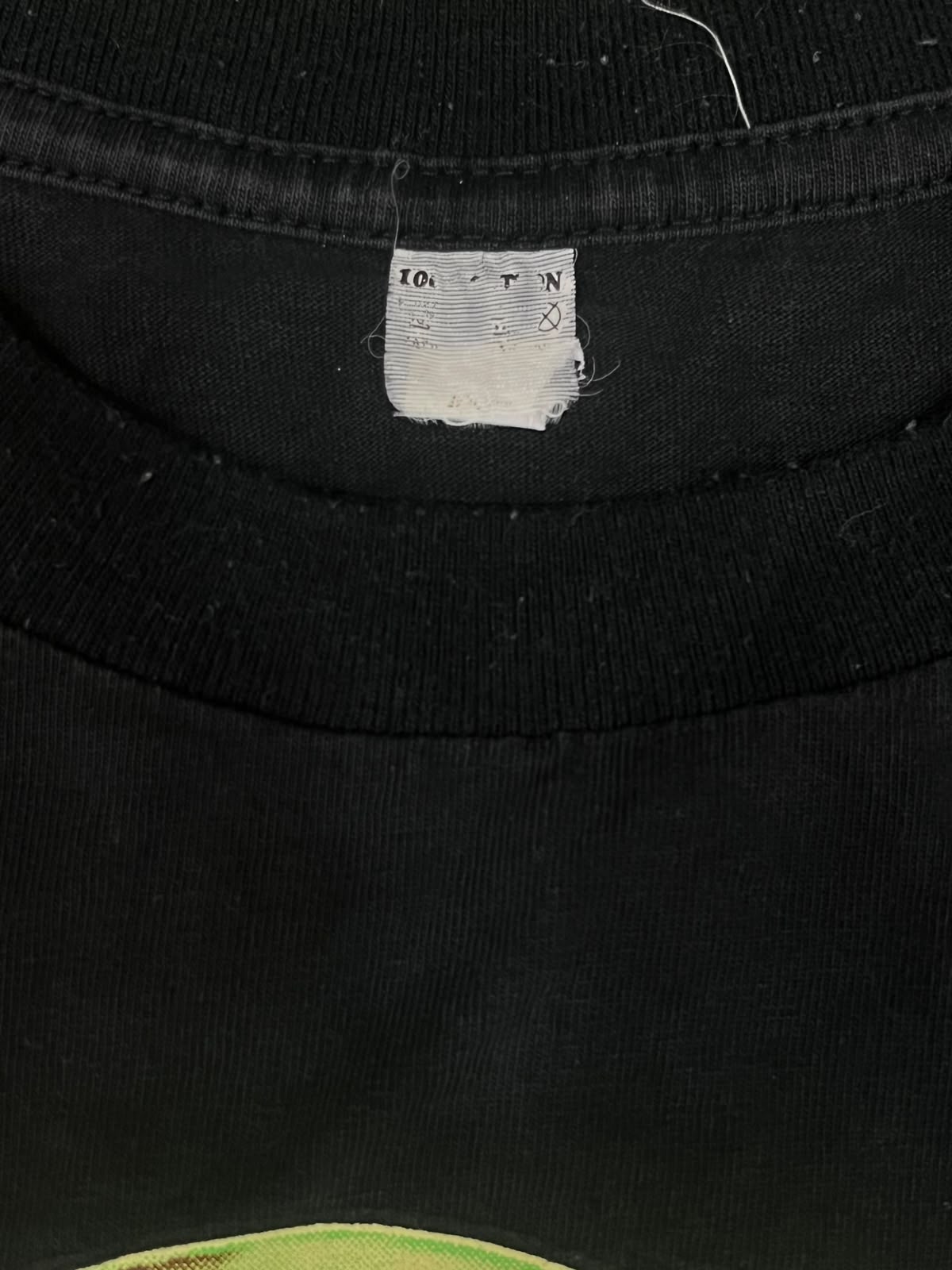 Close-up of a black cotton t-shirt neck label showing the brand '10 for 1' and size information.