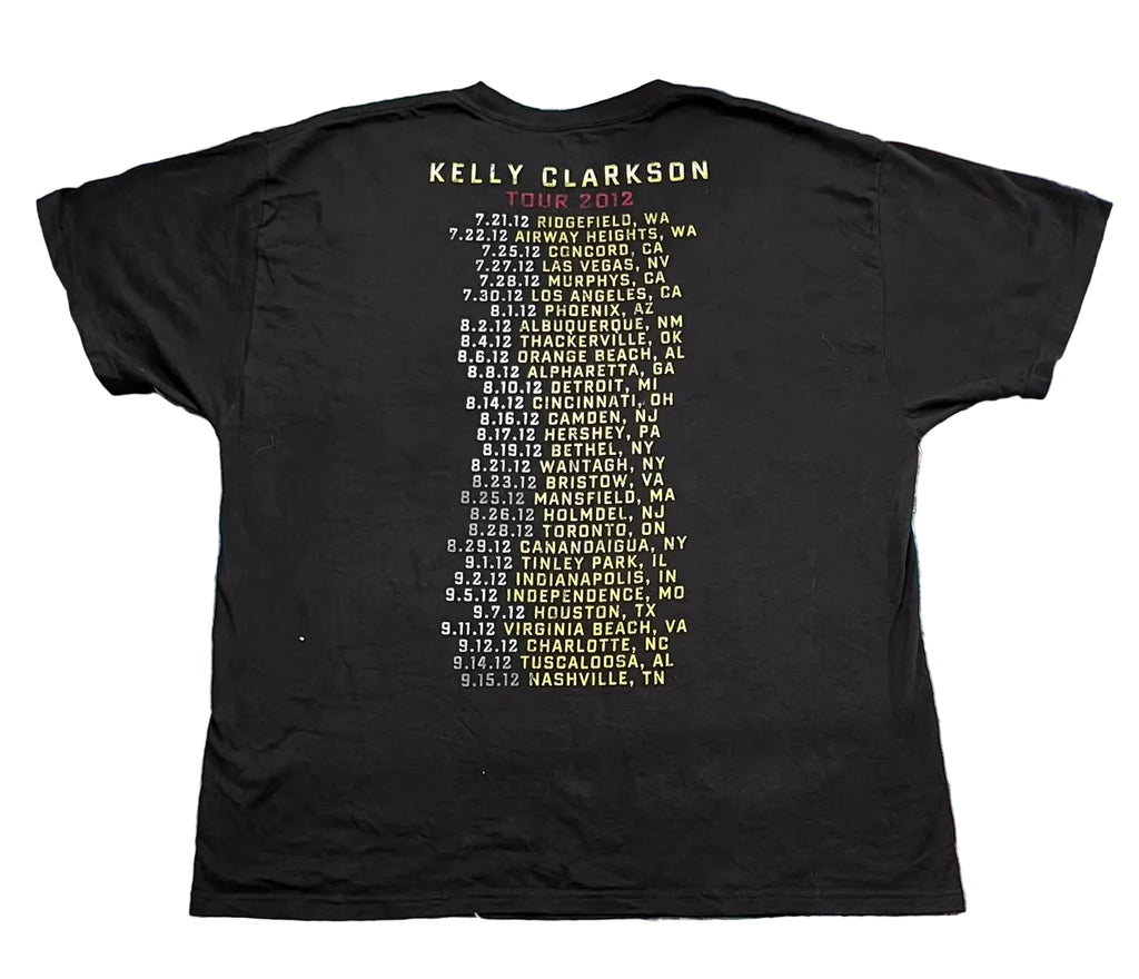 A black short-sleeve T-shirt showing the back side printed with the text 'KELLY CLARKSON' and a concert tour city-and-date list in pale yellow.