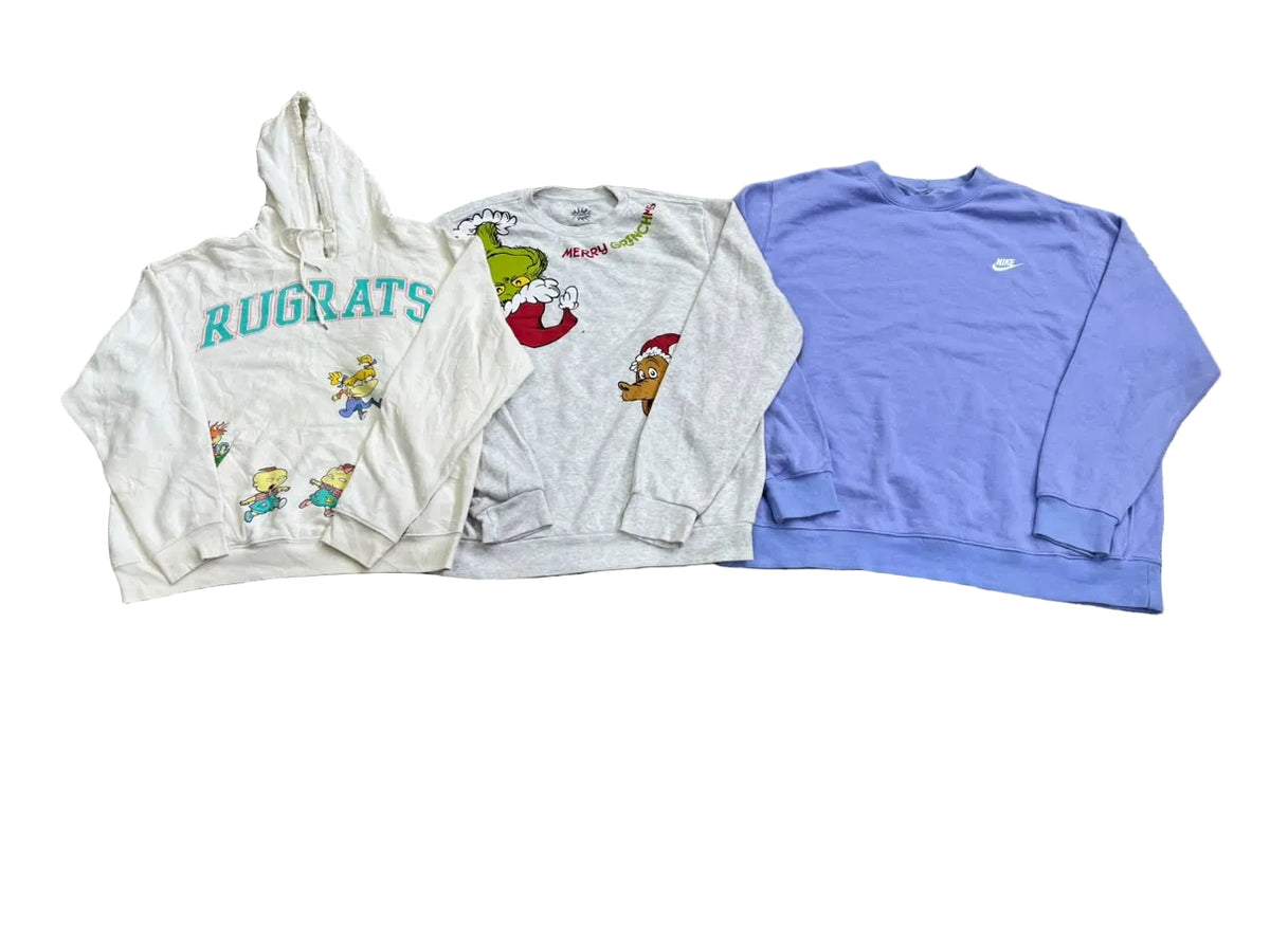Three vintage sweatshirts a cream hoodie with teal 'RUGRATS' text and cartoon graphics, a light gray sweatshirt with Grinch-themed graphics, and a light purple crewneck sweatshirt with a small white Nike logo.
