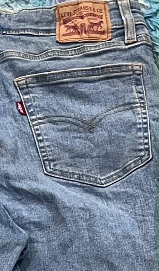 Close-up of the back of a pair of blue Levi's denim jeans, showing the leather brand patch at the waistband and the iconic pocket design.